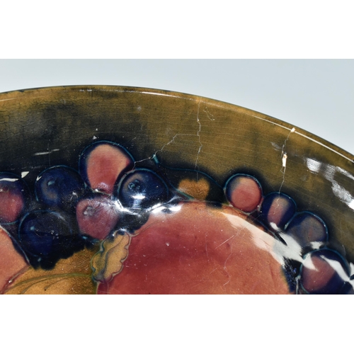 394 - A WILLIAM MOORCROFT SHALLOW FRUIT BOWL DECORATED WITH THE POMEGRANATE PATTERN ON A BLUE / BROWN GREE... 