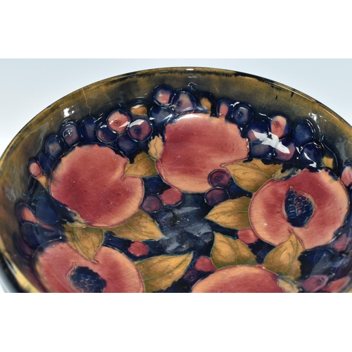 394 - A WILLIAM MOORCROFT SHALLOW FRUIT BOWL DECORATED WITH THE POMEGRANATE PATTERN ON A BLUE / BROWN GREE... 