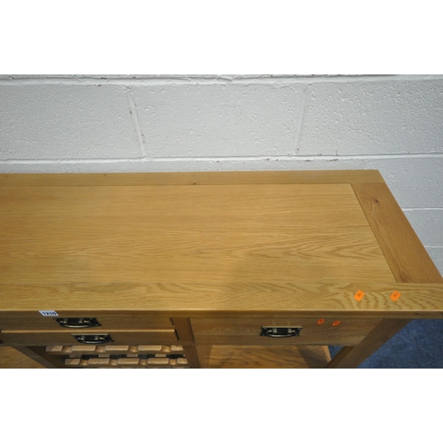 1210 - A SOLID OAK SIDEBOARD, fitted with an arrangement of four drawers and a central three tier wine rack... 