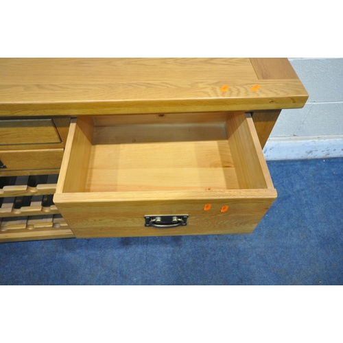 1210 - A SOLID OAK SIDEBOARD, fitted with an arrangement of four drawers and a central three tier wine rack... 