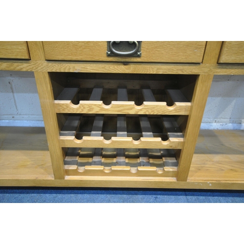 1210 - A SOLID OAK SIDEBOARD, fitted with an arrangement of four drawers and a central three tier wine rack... 