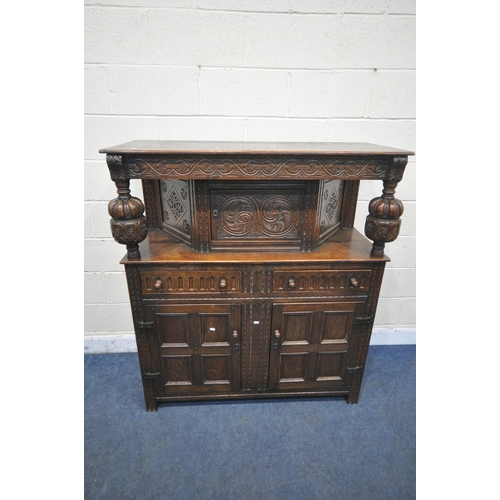 1256 - A 20TH CENTURY OAK COURT CUPBOARD, the top with a single cupboard door, scrolled and foliate carved ... 