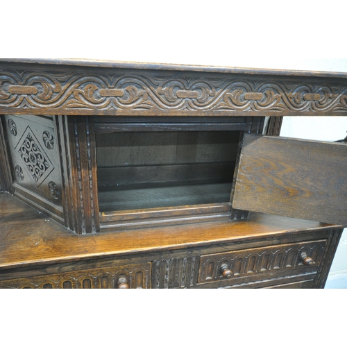 1256 - A 20TH CENTURY OAK COURT CUPBOARD, the top with a single cupboard door, scrolled and foliate carved ... 