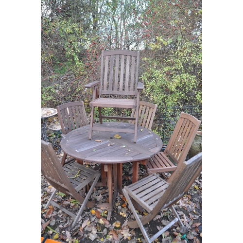 1005 - A STAINED TEAK CIRCULAR GATE LEG GARDEN TABLE, diameter 120cm x height 77cm, and six folding chairs ... 