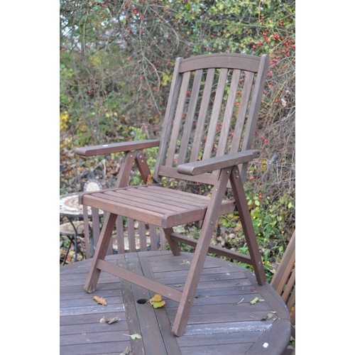 1005 - A STAINED TEAK CIRCULAR GATE LEG GARDEN TABLE, diameter 120cm x height 77cm, and six folding chairs ... 