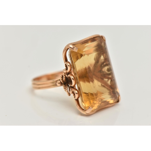 28 - A CITRINE RING, designed as a large rectangular citrine in a four claw setting to the loop design ga... 