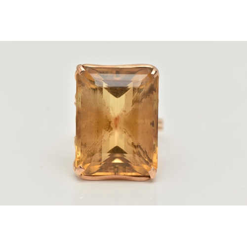 28 - A CITRINE RING, designed as a large rectangular citrine in a four claw setting to the loop design ga... 