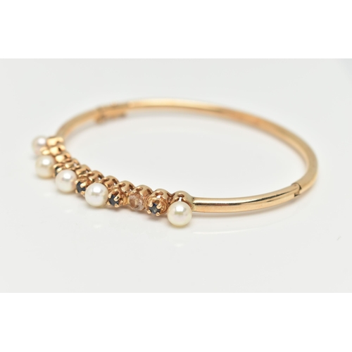 35 - A 9CT GOLD GEM SET BANGLE, designed with a row of five cultured pearls (one pearl is missing), inter... 