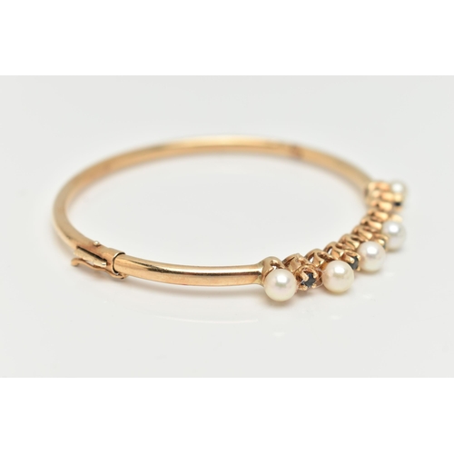 35 - A 9CT GOLD GEM SET BANGLE, designed with a row of five cultured pearls (one pearl is missing), inter... 