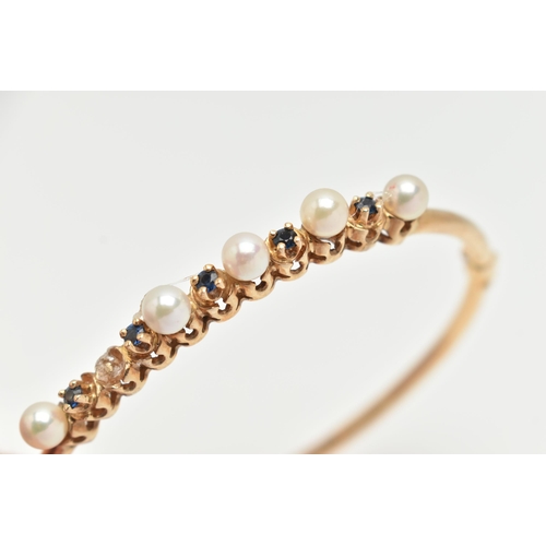 35 - A 9CT GOLD GEM SET BANGLE, designed with a row of five cultured pearls (one pearl is missing), inter... 