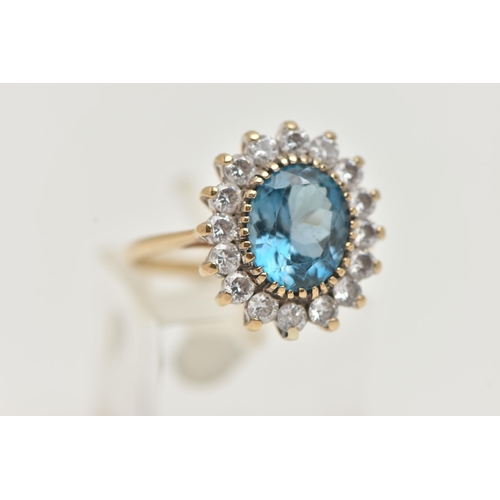 49 - A 9CT GOLD CLUSTER RING, centring on an oval cut blue topaz, in a surround of colourless cubic zirco... 