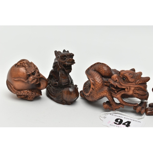 94 - FOUR 20TH CENTURY CARVED TREEN NETSUKE AND TWO OKIMONO, all in the form of dragons, all with inset e... 