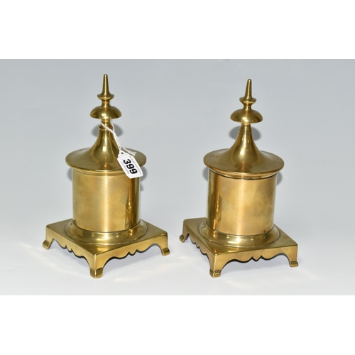 399 - TWO BRASS TOBACCO JARS, with covers, the jars of cylindrical form supported on four feet, height 23c... 