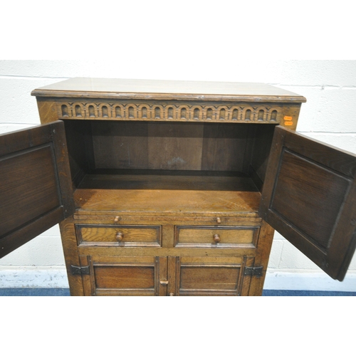 1209 - A 20TH CENTURY SOLID OAK CABINET, fitted with two cupboard doors, carved with an archway, a brushing... 