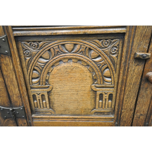 1209 - A 20TH CENTURY SOLID OAK CABINET, fitted with two cupboard doors, carved with an archway, a brushing... 