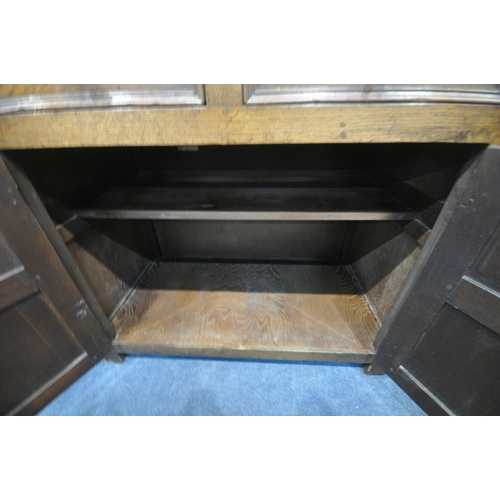 1209 - A 20TH CENTURY SOLID OAK CABINET, fitted with two cupboard doors, carved with an archway, a brushing... 