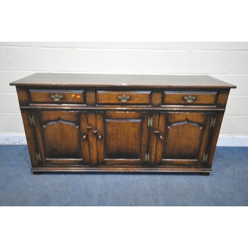 1210 - IN THE MANNER OF TITCHMARSH AND GOODWIN, A SOLID OAK SIDEBOARD, with three drawers above three cupbo... 