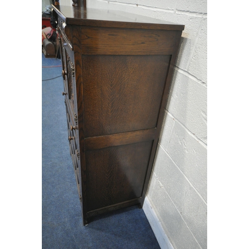 1211 - A 20TH CENTURY SOLID OAK DRINKS CABINET, the two double doors , carved with a seated person, an arch... 