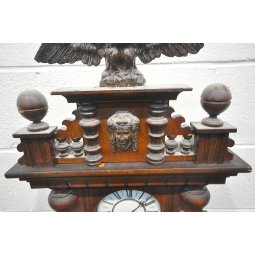 1237 - A LATE 19TH CENTURY WALNUT CASED VIENNA WALL CLOCK, with an eagle pediment, above a human mask, flan... 