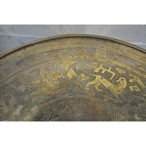 1268 - A CIRCULAR BRASS TOP FOLDING TABLE, the top depicting hunting scenes, etc., on a folding barley twis... 