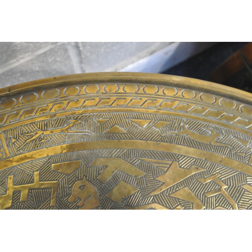 1268 - A CIRCULAR BRASS TOP FOLDING TABLE, the top depicting hunting scenes, etc., on a folding barley twis... 
