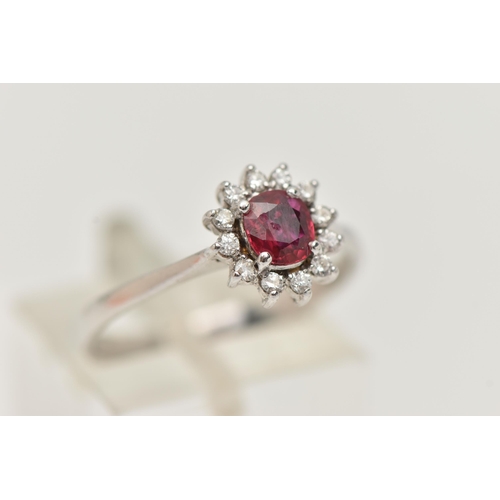 93 - A RUBY AND DIAMOND RING, circular cut ruby prong set in white metal, with a surround of twelve round... 