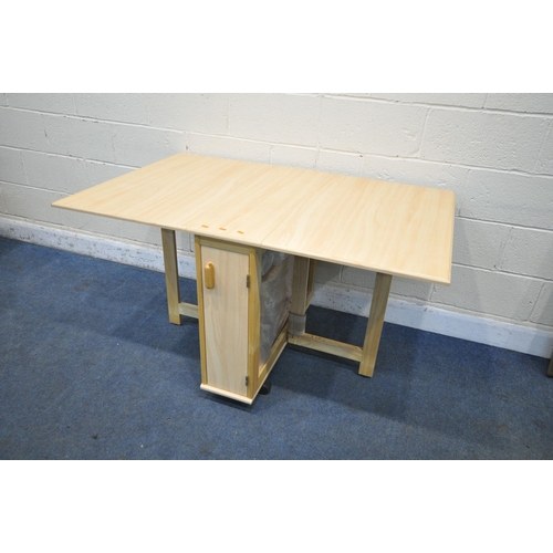 1229 - A MODEN BEECH EFFECT DROP LEAF DINING TABLE, with a single door enclosing four bagged fold away chai... 