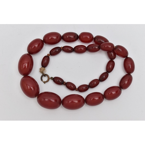 16 - A BAKELITE BEADED NECKLACE, graduated oval cherry amber beads, twenty seven beads in total, approxim... 