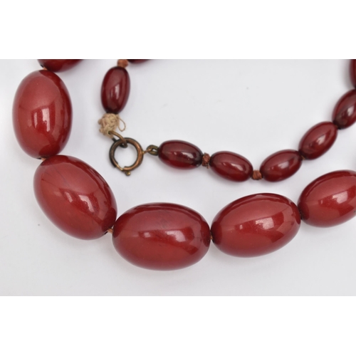 16 - A BAKELITE BEADED NECKLACE, graduated oval cherry amber beads, twenty seven beads in total, approxim... 