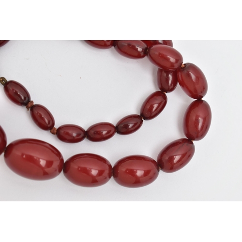 16 - A BAKELITE BEADED NECKLACE, graduated oval cherry amber beads, twenty seven beads in total, approxim... 