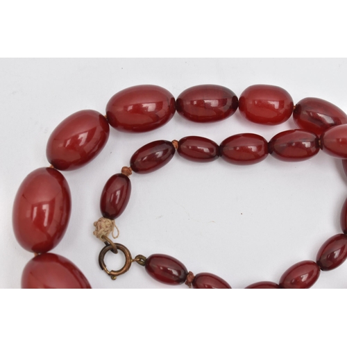 16 - A BAKELITE BEADED NECKLACE, graduated oval cherry amber beads, twenty seven beads in total, approxim... 