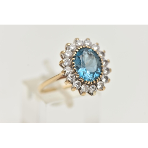 144 - A 9CT GOLD CLUSTER RING, centring on an oval cut blue topaz, in a surround of colourless cubic zirco... 