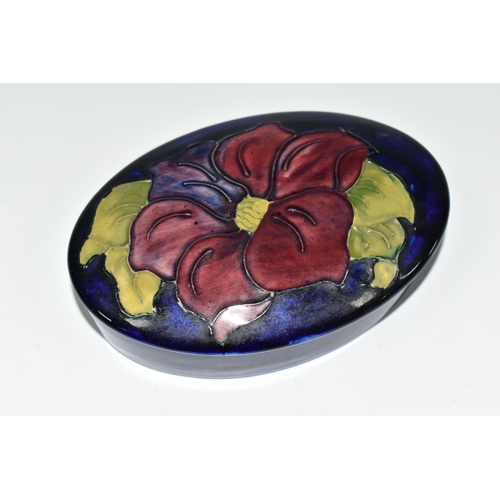 358 - A MOORCROFT POTTERY CLEMATIS TRINKET BOX, the oval box in purple Clematis pattern on a cobalt blue g... 