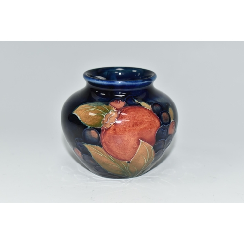 476 - A MOORCROFT POTTERY POMEGRANATE VASE, of squat form, tube lined in Pomegranate pattern on a deep blu... 