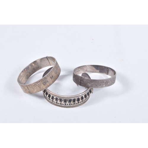 61 - TWO SILVER HINGED BANGLES AND A WHITE METAL CUFF BRACELET, the first a flat hinged bangle with folia... 