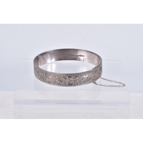 61 - TWO SILVER HINGED BANGLES AND A WHITE METAL CUFF BRACELET, the first a flat hinged bangle with folia... 