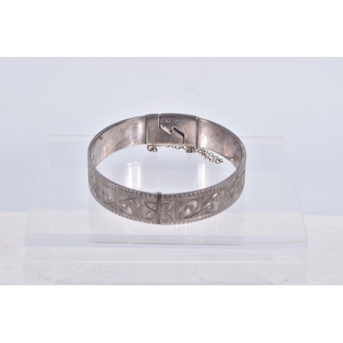 61 - TWO SILVER HINGED BANGLES AND A WHITE METAL CUFF BRACELET, the first a flat hinged bangle with folia... 