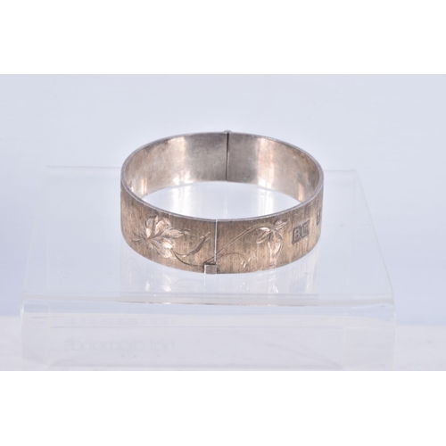 61 - TWO SILVER HINGED BANGLES AND A WHITE METAL CUFF BRACELET, the first a flat hinged bangle with folia... 