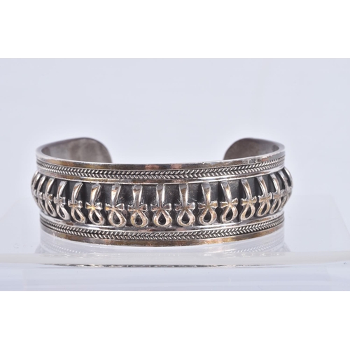 61 - TWO SILVER HINGED BANGLES AND A WHITE METAL CUFF BRACELET, the first a flat hinged bangle with folia... 