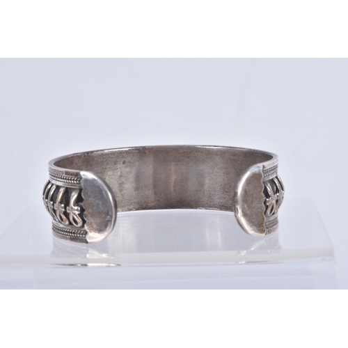 61 - TWO SILVER HINGED BANGLES AND A WHITE METAL CUFF BRACELET, the first a flat hinged bangle with folia... 