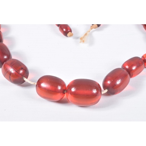 70 - A SINGLE STRAND OF GRADUATED RED PLASTIC BEADS, twenty four oval red beads, largest measuring 29.1mm... 