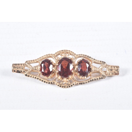 97 - A 9CT GOLD RING AND YELLOW METAL BROOCH, an oval cut garnet, prong set in yellow gold leading on to ... 