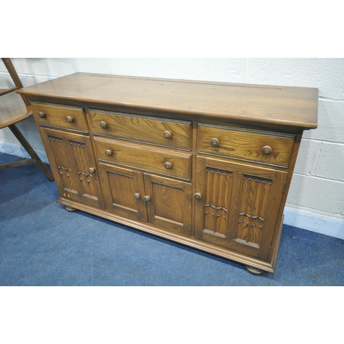 1229 - AN ERCOL ELM AND BEECH CANTERBURY SIDEBOARD, fitted with an arrangement of four drawers and doors, o... 