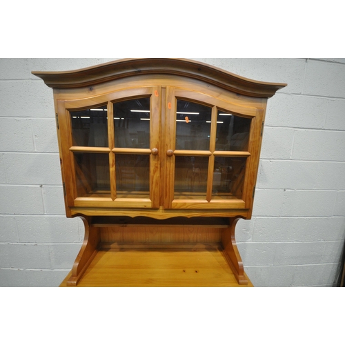 1254 - A MODERN PINE DRESSER, the domed top with two glazed doors, the base with two drawers and two cupboa... 