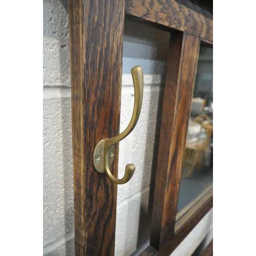 1295 - A 20TH CENTURY OAK HALL STAND, with four brass hooks, surrounding a rectangular bevelled edge mirror... 