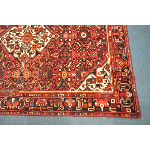 1416 - A RED WOOLEN PERSIAN RUG, with geometric patterns, central medallion, and multi strap border, 215cm ... 