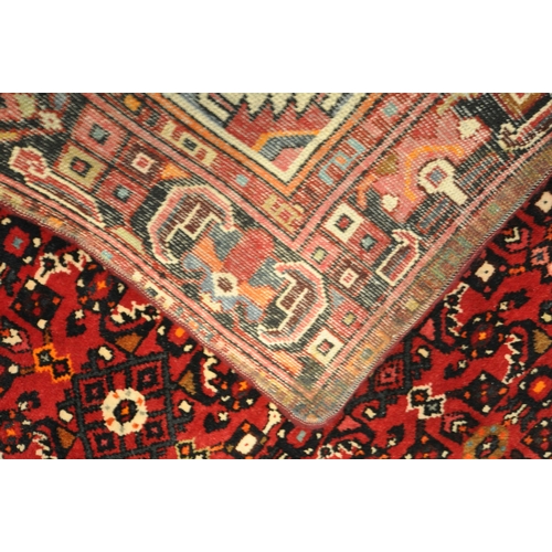 1416 - A RED WOOLEN PERSIAN RUG, with geometric patterns, central medallion, and multi strap border, 215cm ... 