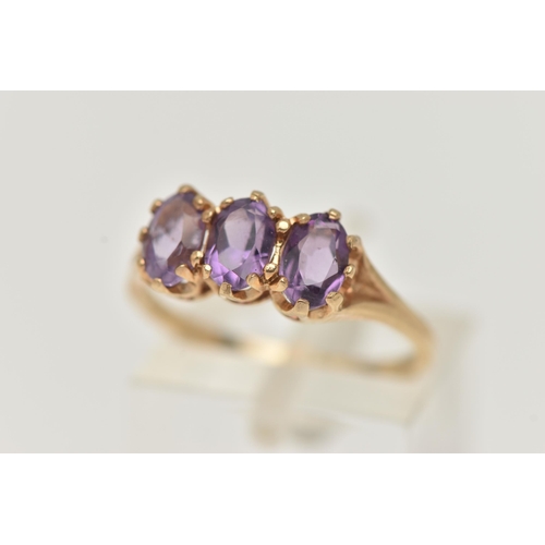 100 - A 9CT GOLD AMETHYST RING, set with three oval cut amethysts, each claw set to the bifurcated shoulde... 