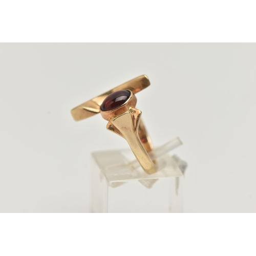 105 - A 9CT GOLD GARNET DRESS RING, abstract design set with an oval garnet cabochon, collet set between a... 