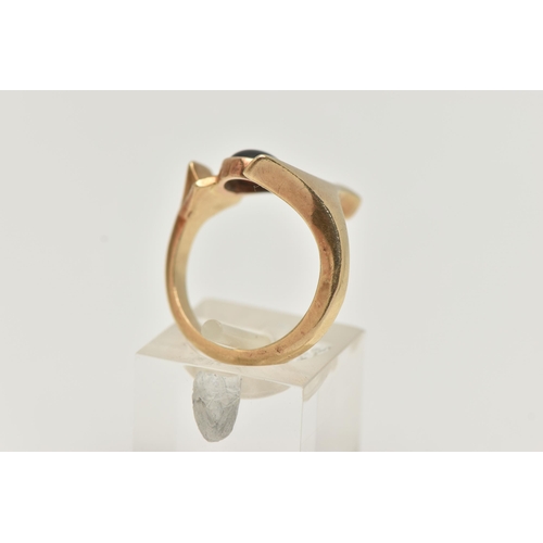 105 - A 9CT GOLD GARNET DRESS RING, abstract design set with an oval garnet cabochon, collet set between a... 